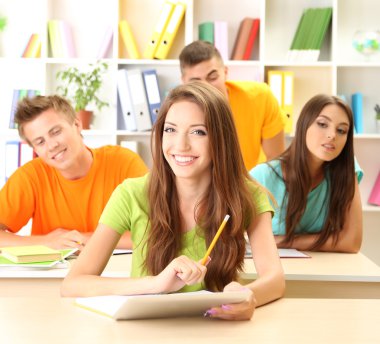 Kütüphanede oturan genç öğrenci grubu