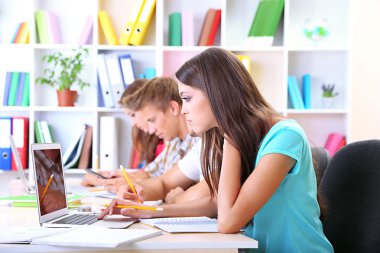 Kütüphanede oturan genç öğrenci grubu