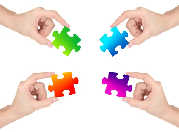 Čtyři ruce držící barevné puzzle, izolované na bílém — Stock fotografie