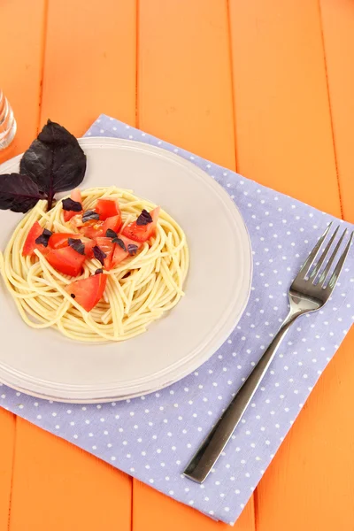 Spaghetti mit Tomaten und Basilikumblättern auf Serviette auf Holzgrund — Stockfoto