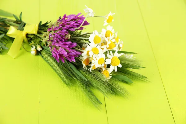 Wild flowers and green spikelets, on wooden background — Stock Photo, Image