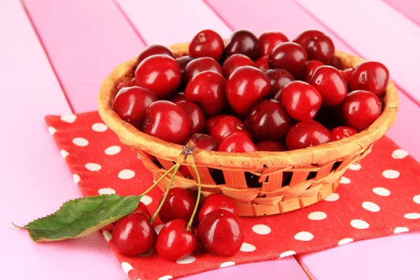 Cherry bessen in rieten mand op houten tafel close-up — Stockfoto