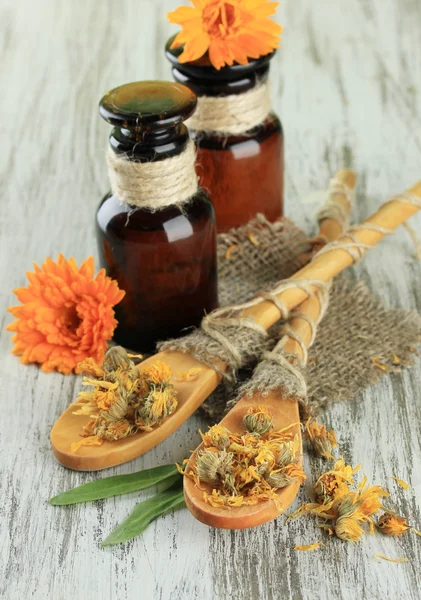 Medicine bottles and calendula flowers on wooden background — Stock Photo, Image