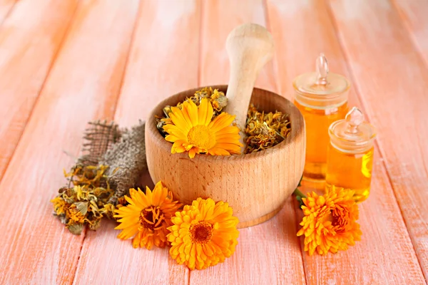 Medicine bottles and calendula flowers on wooden background — Stock Photo, Image