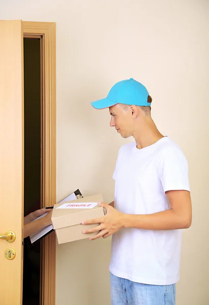 Young delivery man giving parcel — Stock Photo, Image