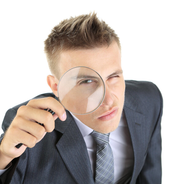Young businessman looking through magnifying glass isolated on white