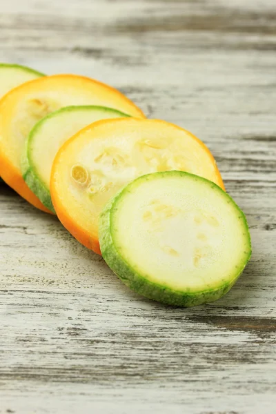 Gele en groene ruwe courgette gesneden op houten tafel — Stockfoto