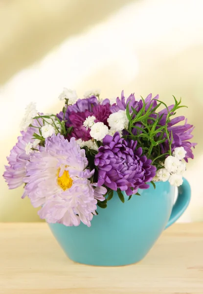 밝은 배경에 나무 테이블에 컬러 머그잔에 밝은 꽃의 아름 다운 부케 — 스톡 사진