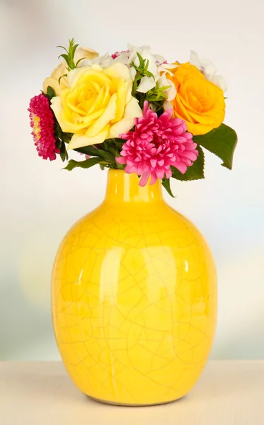 Vacker bukett av ljusa blommor i vas, färg, på träbord, på ljus bakgrund — Stockfoto