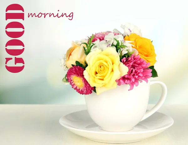 マグカップの色、明るい背景上の木製のテーブルの上に鮮やかな花の美しい花束 — ストック写真