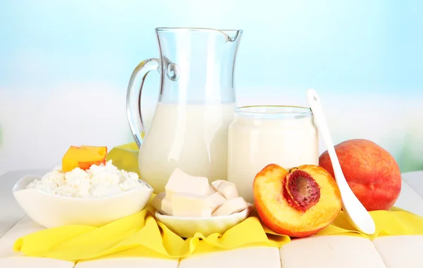 Frische Milchprodukte mit Pfirsichen auf Holztisch vor natürlichem Hintergrund — Stockfoto