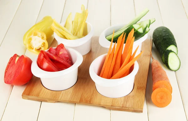 Légumes frais brillants coupés en tranches dans des bols sur une table en bois close-up — Photo