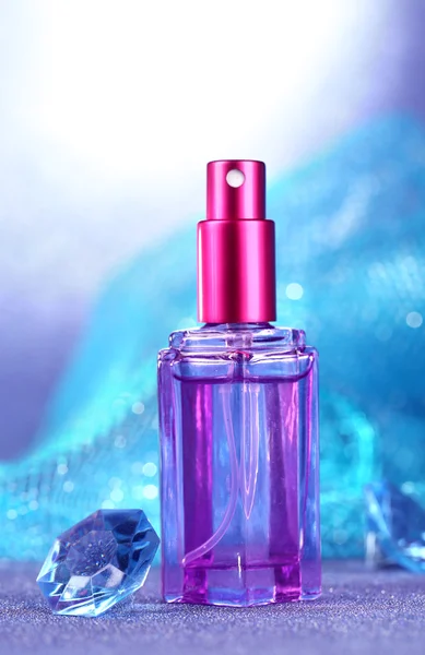 Perfume de mujer en hermosa botella sobre fondo azul —  Fotos de Stock