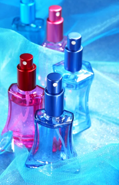 Women perfume in beautiful bottles on blue background — Stock Photo, Image