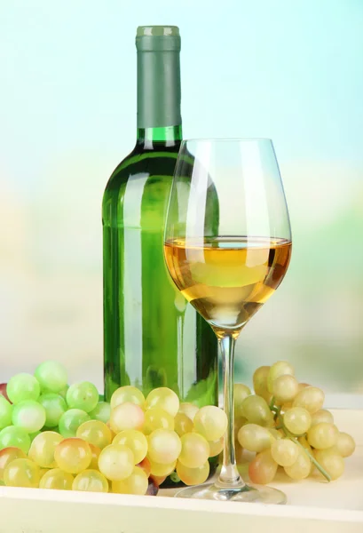 Bottiglia di vino e bicchiere di vino su vassoio, su sfondo luminoso — Foto Stock