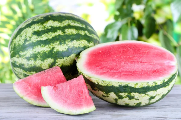 Reife Wassermelonen auf Holztisch auf Naturhintergrund — Stockfoto