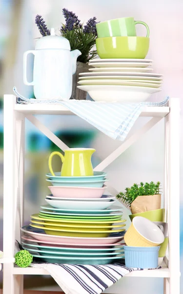 Beautiful white shelves with tableware and decor, on bright background, close-up — Stock Photo, Image