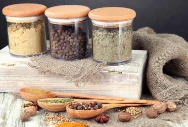 tahta kaşıklar ve ahşap zemin üzerinde cam kavanozlar içinde baharat çeşitleri