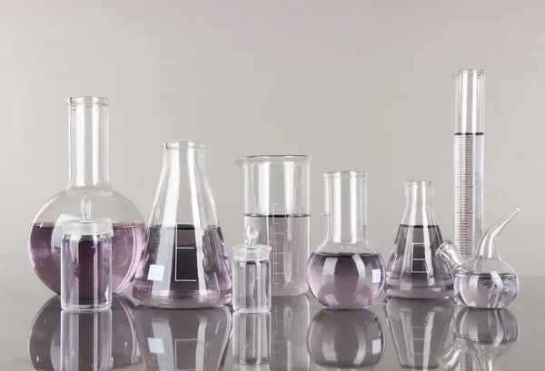 Тестовые трубки со светло-фиолетовой жидкостью на сером фоне — стоковое фото