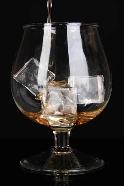 Brandy versando in vetro su sfondo nero — Foto Stock