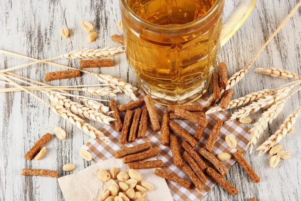 Cerveza en crujidos de vidrio, y nueces en servilleta en mesa de madera — Foto de Stock