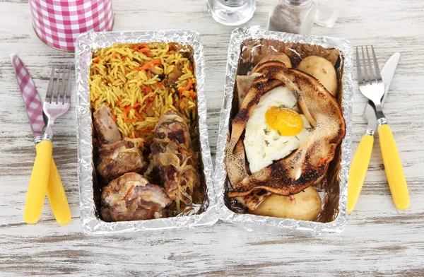 Food in boxes of foil on wooden table