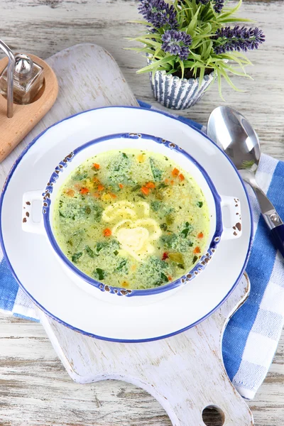 Soup in plate on napkin on wooden board on table — Stock Photo, Image