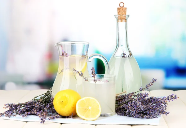 Lavender lemonade in glass bottle and jug, on napkin, on bright background — Stock Photo, Image