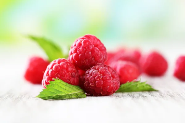 Rijpe zoete frambozen op houten tafel, op groene achtergrond — Stockfoto