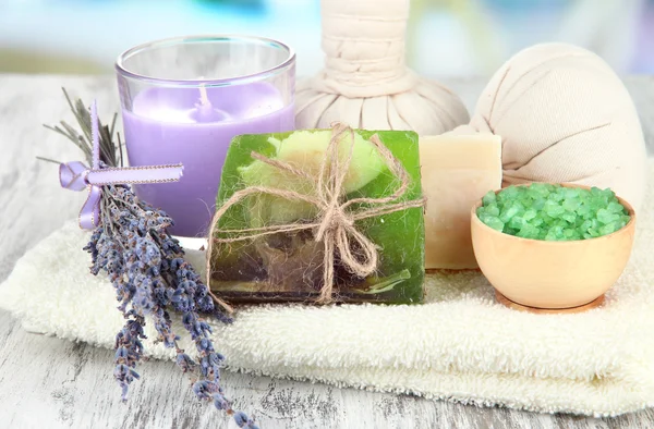 Stillleben mit Lavendelkerze, Seife, Massagekugeln, Flaschen, Seife und frischem Lavendel, auf Holztisch vor hellem Hintergrund — Stockfoto