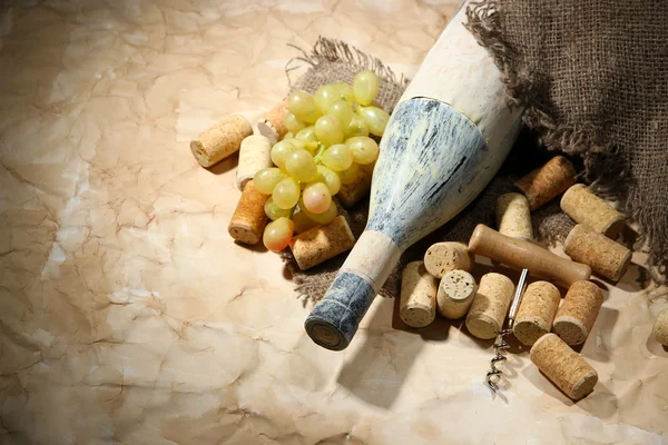 Old bottle of wine, grapes and corks on old paper background — Stock Photo, Image