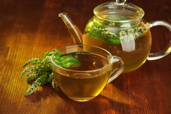 Cup and teapot of herbal tea with fresh mint flowers on wooden table — Stock Photo, Image