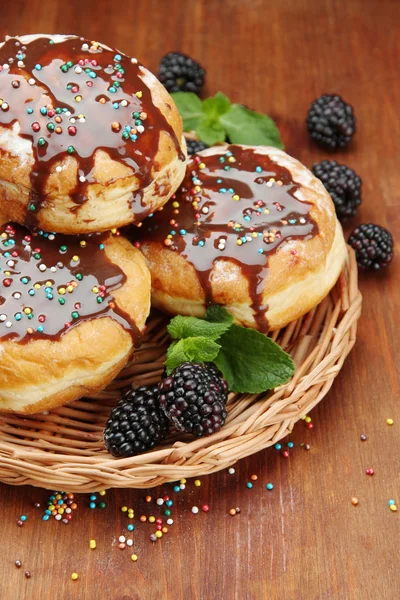 Leckere Donuts mit Schokolade und Beeren auf Holztisch — Stockfoto