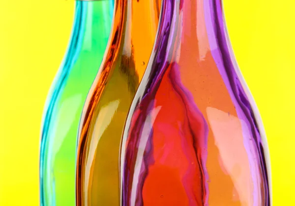 Kolorowe butelki na żółtym tle — Zdjęcie stockowe
