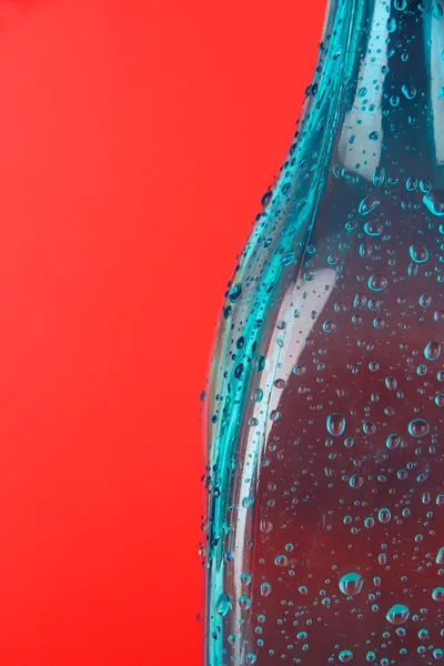 Barevná láhev na červeném pozadí — Stock fotografie