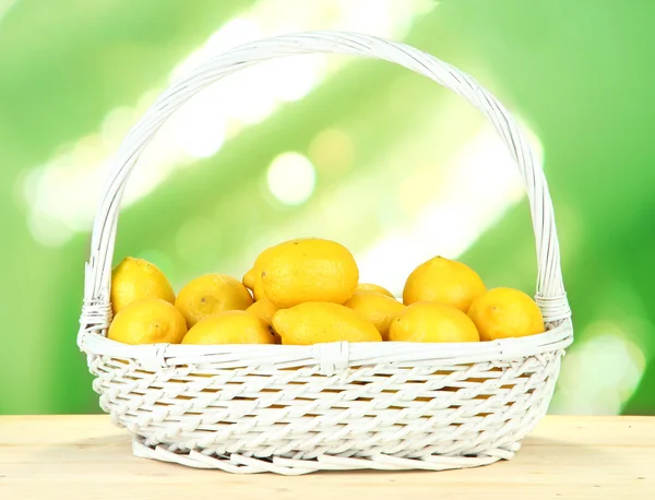 Citrons mûrs dans le panier en osier sur la table sur fond lumineux — Photo