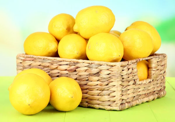 Limones maduros en canasta de mimbre sobre mesa sobre fondo brillante —  Fotos de Stock