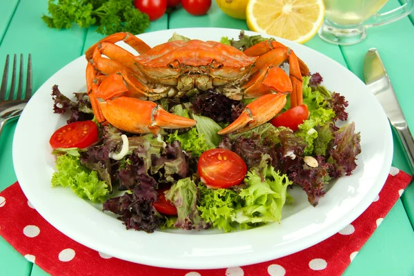 Gekookte krab op wit bord met salade bladeren en tomaten, op houten tafel achtergrond — Stockfoto