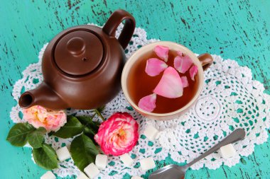 Kettle ve çay gülü gemide peçete ahşap zemin üzerinde gelen