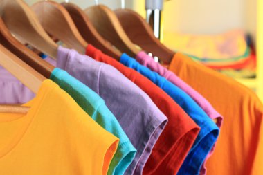 çeşitli ahşap askı raf arka plan üzerinde rahat t-shirt