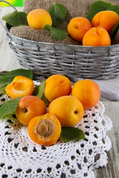 Apricots in basket on napkin on wooden table — Stock Photo, Image