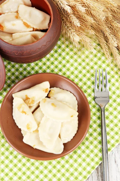 Tasty dumplings with fried onion on brown plate, on wooden background — Stock Photo, Image