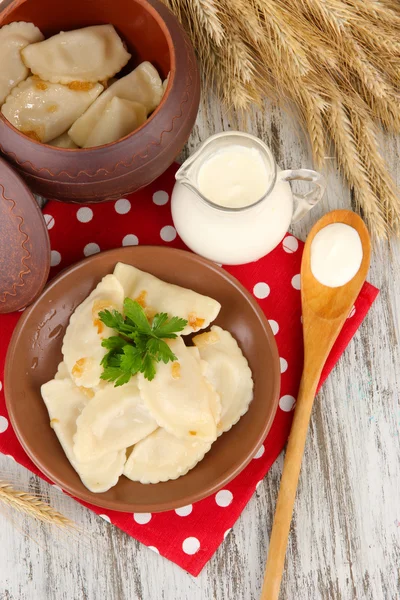 Gnocchi gustosi con cipolla fritta su piatto marrone, su fondo di legno — Foto Stock