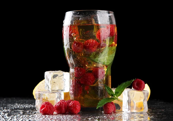 Iced tea with raspberries and mint on dark background with yellow light — Stock Photo, Image