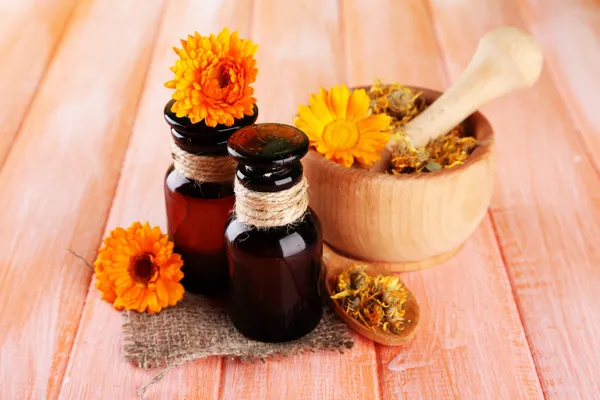 Geneeskundeflessen en calendula bloemen op houten achtergrond — Stockfoto