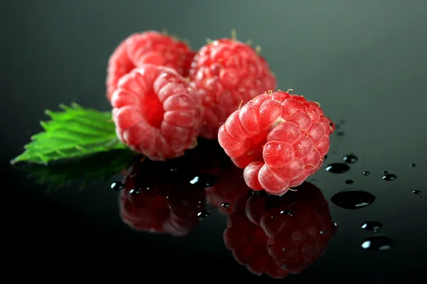 Framboises douces mûres avec des gouttes sur fond sombre — Photo