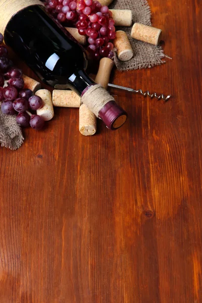 Şişe şarap, üzüm ve ahşap zemin üzerinde mantarlar — Stok fotoğraf