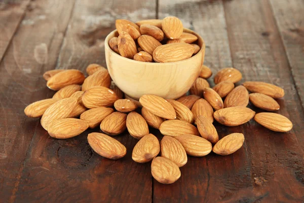 Almond di mangkuk kayu, di latar belakang kayu — Stok Foto