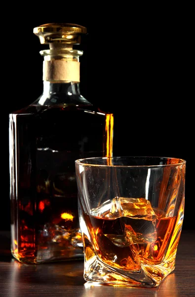 Glass of whiskey with bottle, on dark background — Stock Photo, Image