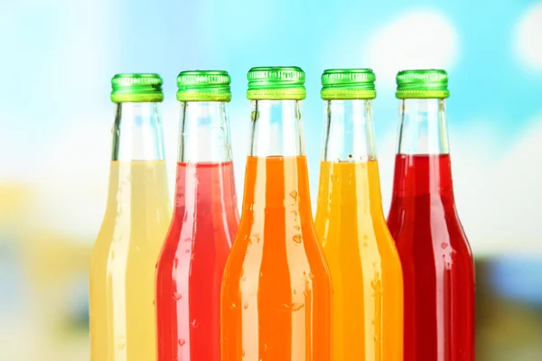 Botellas con bebidas sabrosas sobre fondo brillante — Foto de Stock